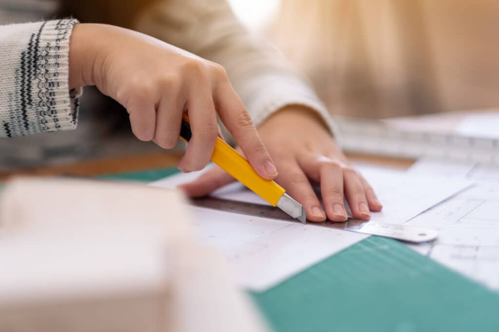 An architect working and cutting papers in office