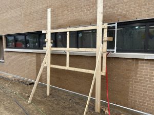 Engineer conducting AAMA 501.2 nozzle testing, using a spray wand to identify leaks on a building exterior at Lamar University.