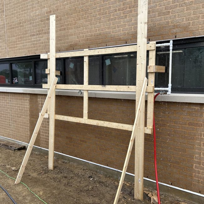 Engineer conducting AAMA 501.2 nozzle testing, using a spray wand to identify leaks on a building exterior at Lamar University.