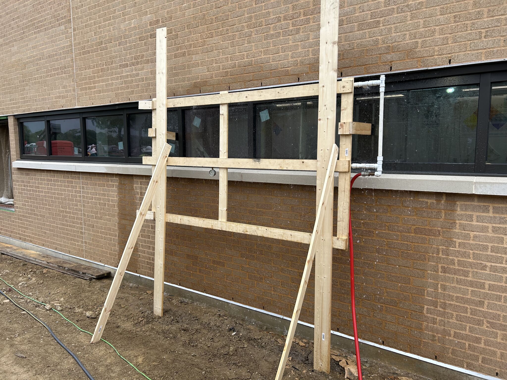 Engineer conducting AAMA 501.2 nozzle testing, using a spray wand to identify leaks on a building exterior at Lamar University.