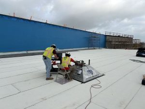 Technicians conducting ASTM E907 Roof Uplift Testing on a commercial building roof during an early morning session.