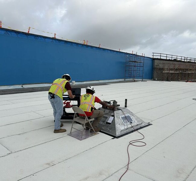 Technicians conducting ASTM E907 Roof Uplift Testing on a commercial building roof during an early morning session.